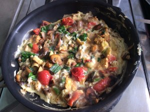 Eggs and fresh vegetables in a breakfast scramble including tomatoes, spinach, mushrooms and spring onions 