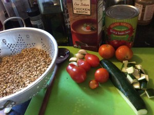 Lentils, tomatoes, onion, on cutting board to be made into Lentil soup