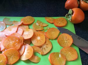 Sliced fresh persimmons on a green cutting surface 