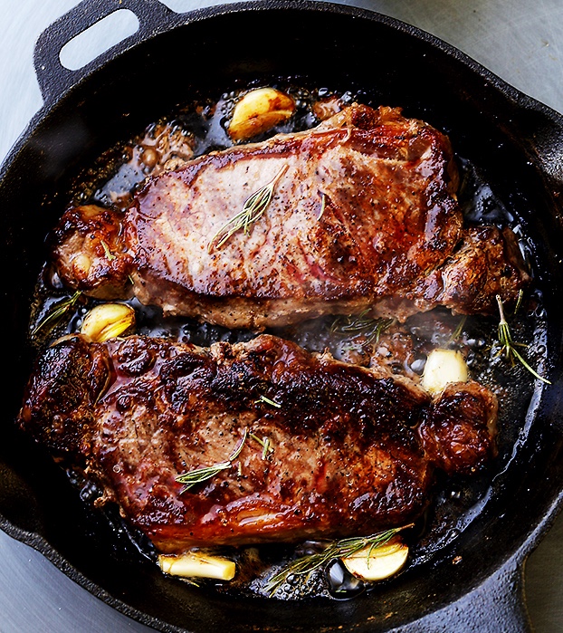 Sirloin steak in pan with garlic cloves